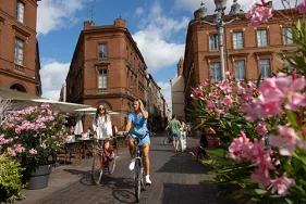Deux jeunes filles font du vélo sur la place du Capitole  (Agrandir l'image - fenêtre modale)