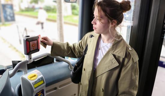 Une jeune femme paie avec sa carte bancaire à la montée du bus (Agrandir l'image - fenêtre modale)